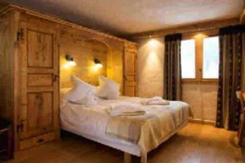 um quarto com uma cama grande e lençóis brancos em Chalet de 3 chambres a Les Allues a 500 m des pistes avec terrasse et wifi em Les Allues