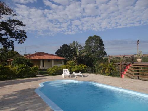 uma casa com piscina e duas cadeiras em Casa em sítio à beira do Rio Piracicaba c/ piscina em São Pedro