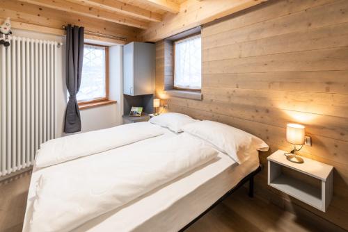 Schlafzimmer mit Holzwänden und einem großen weißen Bett in der Unterkunft B&B Piazza in Fondo