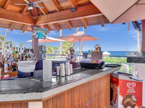 uma mulher sentada num bar com um guarda-chuva em Oceanfront Beach Retreat Beach Service 502 em Miami Beach