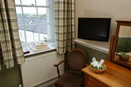 a room with a chair and a television and a window at Portclew House in Pembroke
