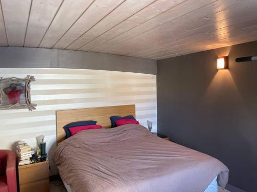 um quarto com uma cama com lençóis cor-de-rosa e almofadas vermelhas em Villa de 3 chambres avec piscine privee terrasse et wifi a Landunvez em Landunvez