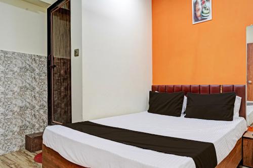 a bedroom with a bed with an orange wall at Super OYO Hotel Orange in Surat