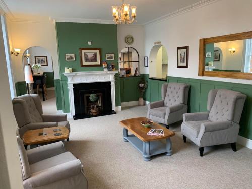uma sala de estar com cadeiras, uma mesa e uma lareira em Abbots Mead Hotel em Shrewsbury