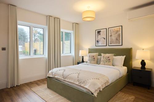 a bedroom with a large bed and two windows at The Wembley Park Secret - Spacious 3BDR Flat with Terrace in London