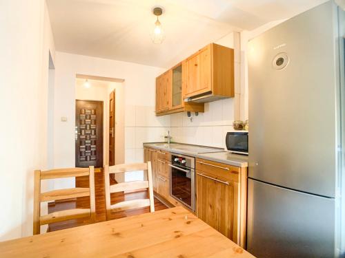 Una cocina con refrigerador de acero inoxidable y gabinetes de madera. en Apartament przy parku, en Toruń