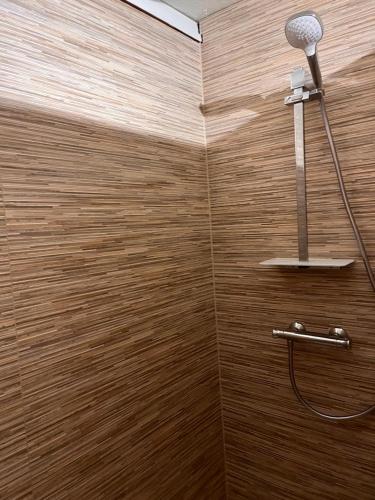 a shower in a bathroom with a wooden wall at Woods House in La Calamine