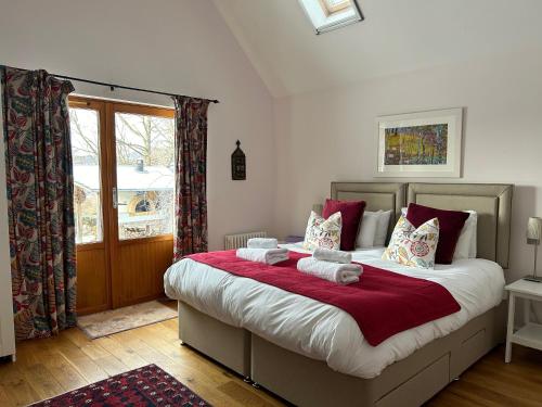 a bedroom with a large bed with red and white pillows at Drumguish Cottage in Kingussie