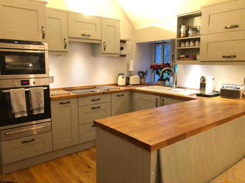 a kitchen with white cabinets and a wooden counter top at Drumguish Cottage in Kingussie
