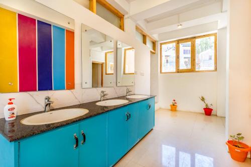 uma casa de banho com 2 lavatórios e uma parede colorida em Downtown Hostel Leh em Leh