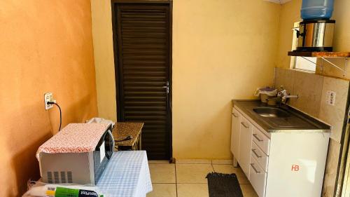 a small kitchen with a sink and a microwave at Pousada Colorado in Olímpia