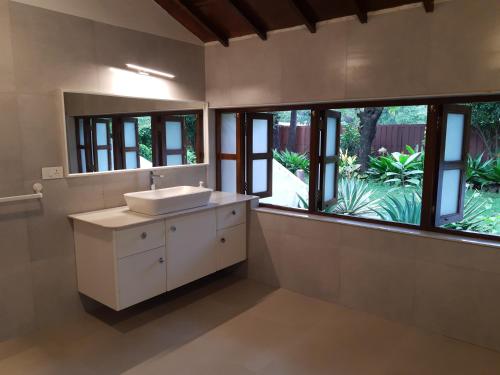 a bathroom with a sink and a large window at Banyan House - luxurious 4 bedroom villa on one acre, near the beach in Nagaon