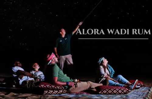 Alora Wadi Rum Luxury في وادي رم: مجموعة من الناس يجلسون على الأرض أمام المسرح