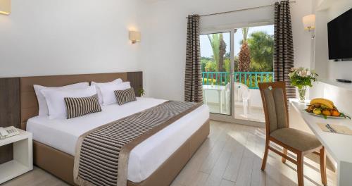 a bedroom with a bed and a table and a balcony at El Mouradi Port El Kantaoui in Port El Kantaoui