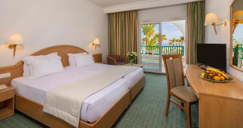 a hotel room with a bed and a desk and a television at El Mouradi Port El Kantaoui in Port El Kantaoui