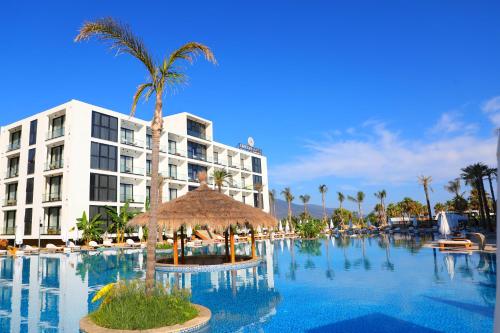 ein großer Swimmingpool mit Palmen und ein Hotel in der Unterkunft Oricon Coast Luxury Resort in Orikum