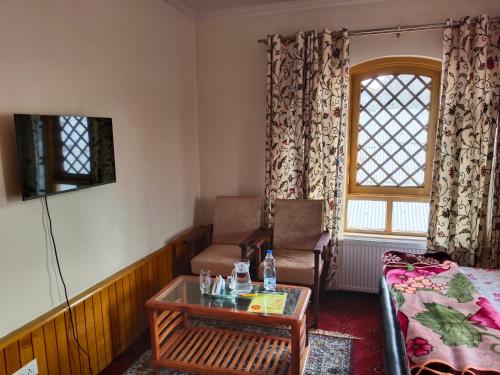 a room with a bed and a table and a chair at Bashaw Residency, Top Rated Family Guest House Near Srinagar Airport in Srinagar