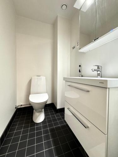 a white bathroom with a toilet and a sink at Stay with locals at Tripla (room) in Helsinki