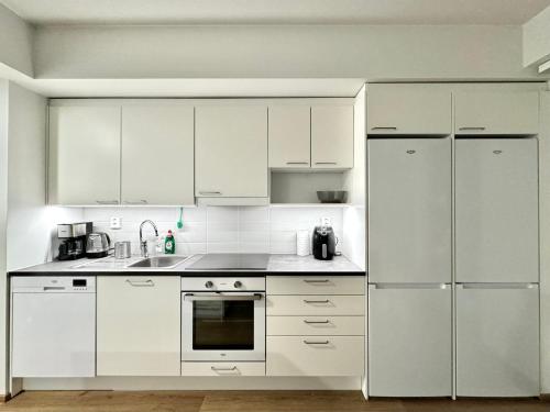 una cocina blanca con electrodomésticos blancos y armarios blancos en Stay with locals at Tripla (room) en Helsinki
