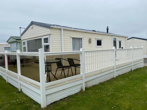 a white deck with a table and chairs on a house at Thistle 83 in Porthcawl