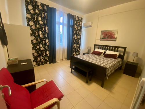 a bedroom with a bed and a red couch at Hermes Apartment - Athens Int Airport in Artemida