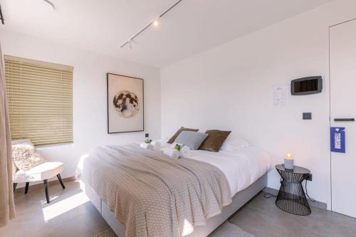um quarto branco com uma cama grande e uma cadeira em Lord - Charming double room at ranch "De Blauwe Zaal" em Bruges