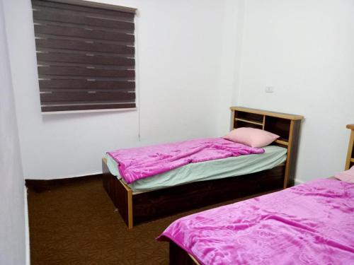 a bedroom with two beds with pink sheets and a window at عجلون- راس منيف in Ajloun