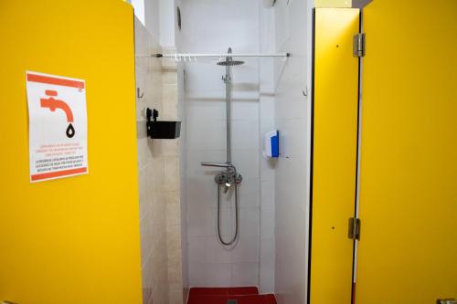 a shower stall in a bathroom with a yellow wall at Onefam Les Corts in Barcelona