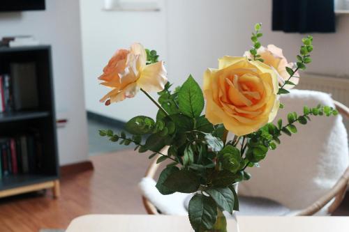 ブラウンラーゲにあるFerienapartment Bergstationの黄橙のバラがテーブルの上に飾られた花瓶