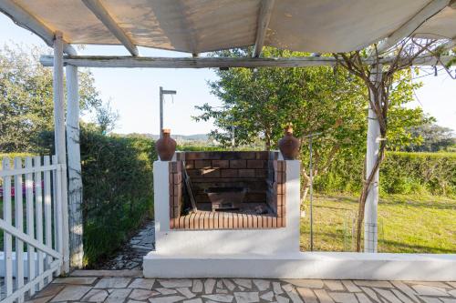 a fireplace on a patio with a white fence at Monte do Cerro in Porto Covo