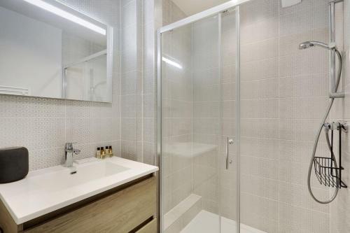 ein Bad mit einer Glasdusche und einem Waschbecken in der Unterkunft Appartement Neuf avec Terrasse in Levallois-Perret
