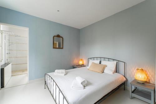 Schlafzimmer mit einem Bett mit weißer Bettwäsche und einem Spiegel in der Unterkunft Magnifique Appartement avec parking a 300m de la Plage in La Teste-de-Buch