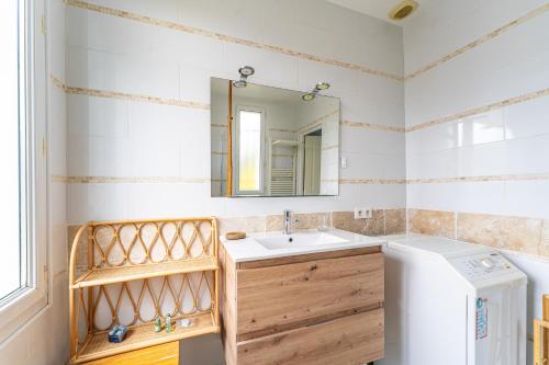 a bathroom with a sink and a washer and dryer at Magnifique Appartement avec parking a 300m de la Plage in La Teste-de-Buch