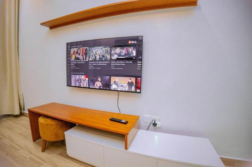 魯亨蓋里的住宿－Makeri Residence - Musanze , Rwanda，挂在白色墙壁上的电视,配有书桌