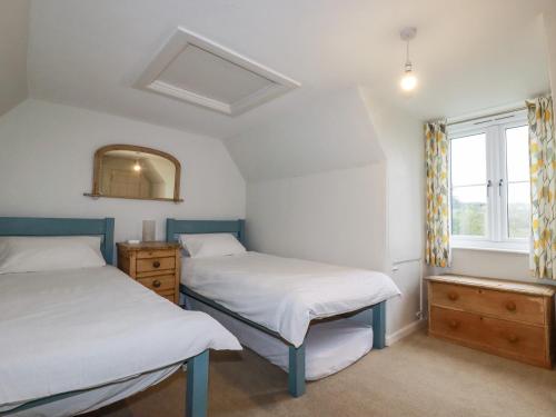 two beds in a room with a window at Lanvean Farmhouse in Newquay