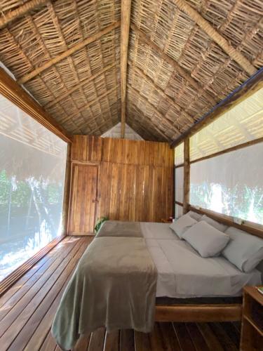 a bed in a room with a wooden ceiling at EcoAraguaia Jungle Lodge in Caseara