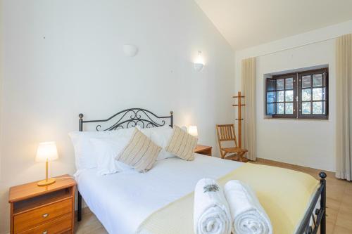 a bedroom with a large white bed with towels on it at Monte do Cerro in Porto Covo