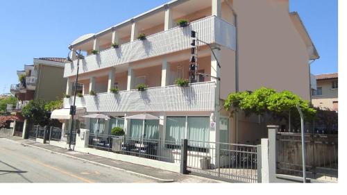 a building with a balcony with tables and umbrellas at Hotel Eliani in Grado