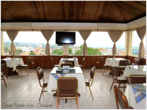a restaurant with tables and chairs and a flat screen tv at Hotel Monte Azul in Tarapoto