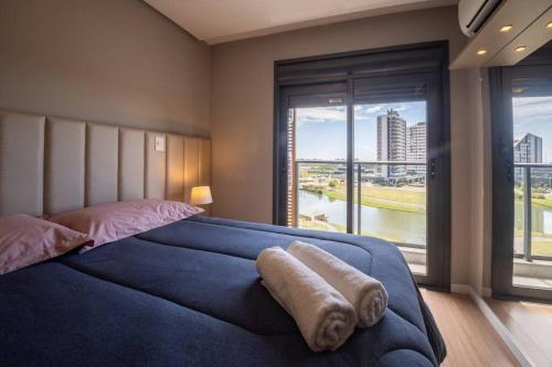 a bedroom with a large bed with a large window at Apto 617 com vista Parque Una in Pelotas