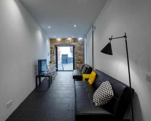 a living room with a black couch and a hallway at El Estudio de La Artista - El casar de Leo in Alburquerque