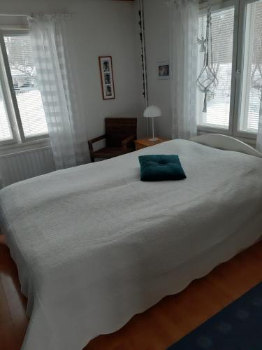 a large white bed with a blue pillow on it at PUUTARHAHUONEISTO CASINONSAARI in Savonlinna