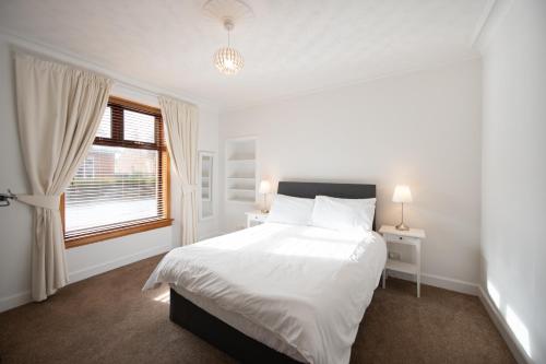 a white bedroom with a large bed and a window at The Prestwick Pad in Prestwick