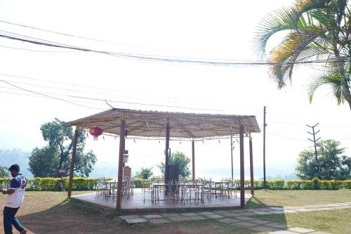 a man walking in front of a pavilion with tables at Nisarga Lake Resort Tapola in Satara