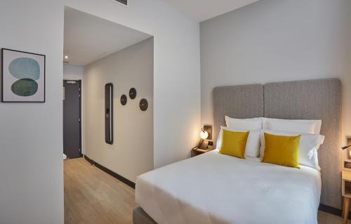 - une chambre avec un grand lit blanc et des oreillers jaunes dans l'établissement Odalys City Nîmes Arènes, à Nîmes