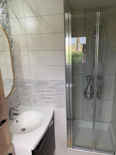 La salle de bains est pourvue d'une douche et d'un lavabo blanc. dans l'établissement Maison 50 m de la Plage Valentin, vue sur mer, à Batz-sur-Mer