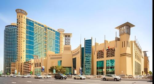 un grand bâtiment avec des voitures garées dans un parking dans l'établissement Cornich AD - Pearl Room, à Abu Dhabi