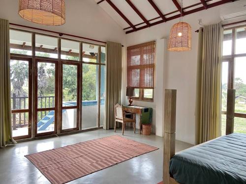a bedroom with a bed and a desk and windows at Wild Ele 243 Wilpattu in Achchamulai