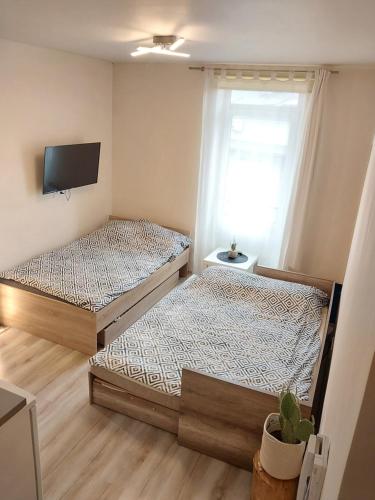 two beds in a room with a tv on the wall at Studio near Old Town in Krakow