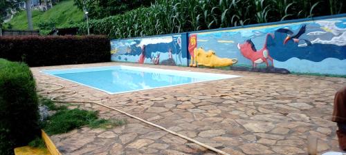 a swimming pool with a painting on a wall at GOOLO guesthouse in Jinja